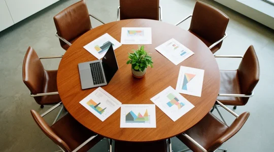 Vue plongeante d'un espace de réunion moderne avec table ronde et documents stratégiques, symbolisant la transformation RH